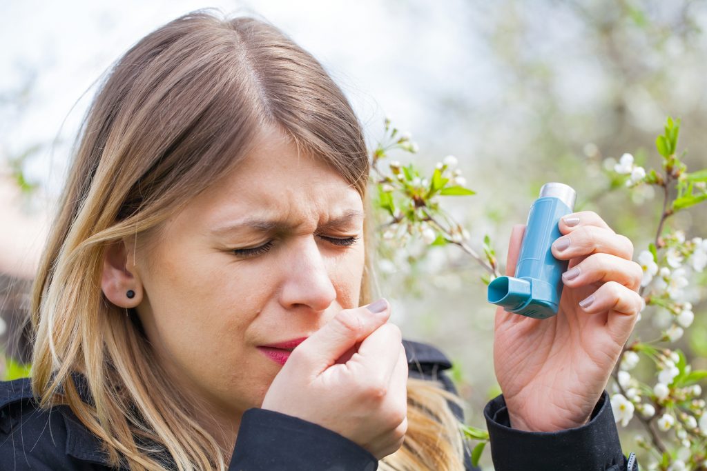 Picture of a young woman having pollen allergy holding a bronchodilator outdoor. Asthmatic Allergenic and Triggers - Medical Equipment Spirometer Calibration